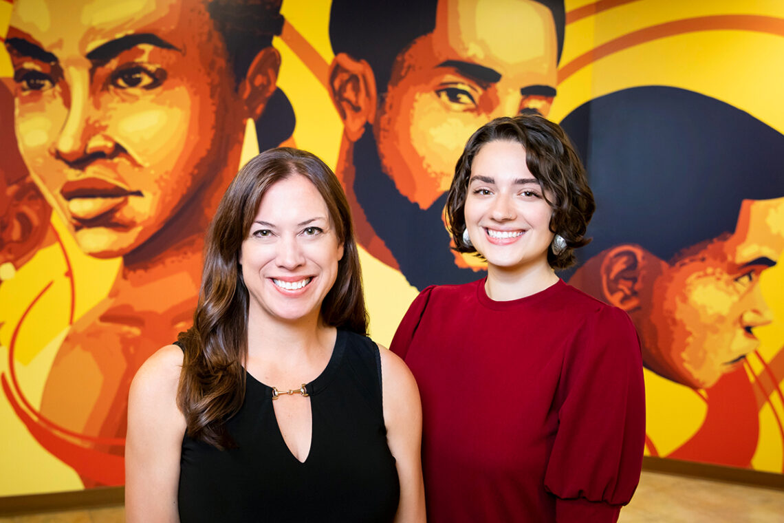 Powell and Muller stand in front of a mural.