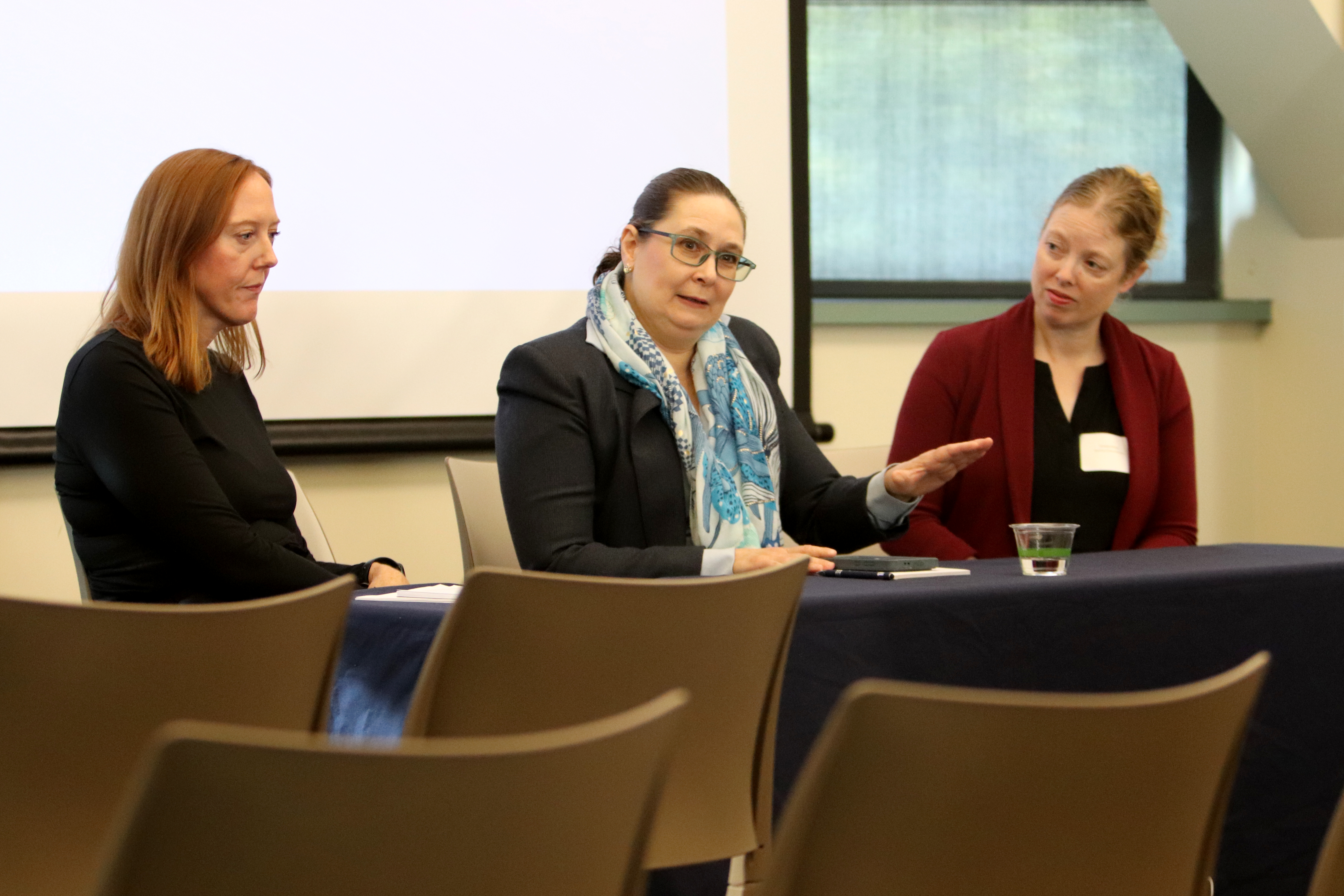 Teran answers question seated at a table while panelists McCoy and Rudolphi listen