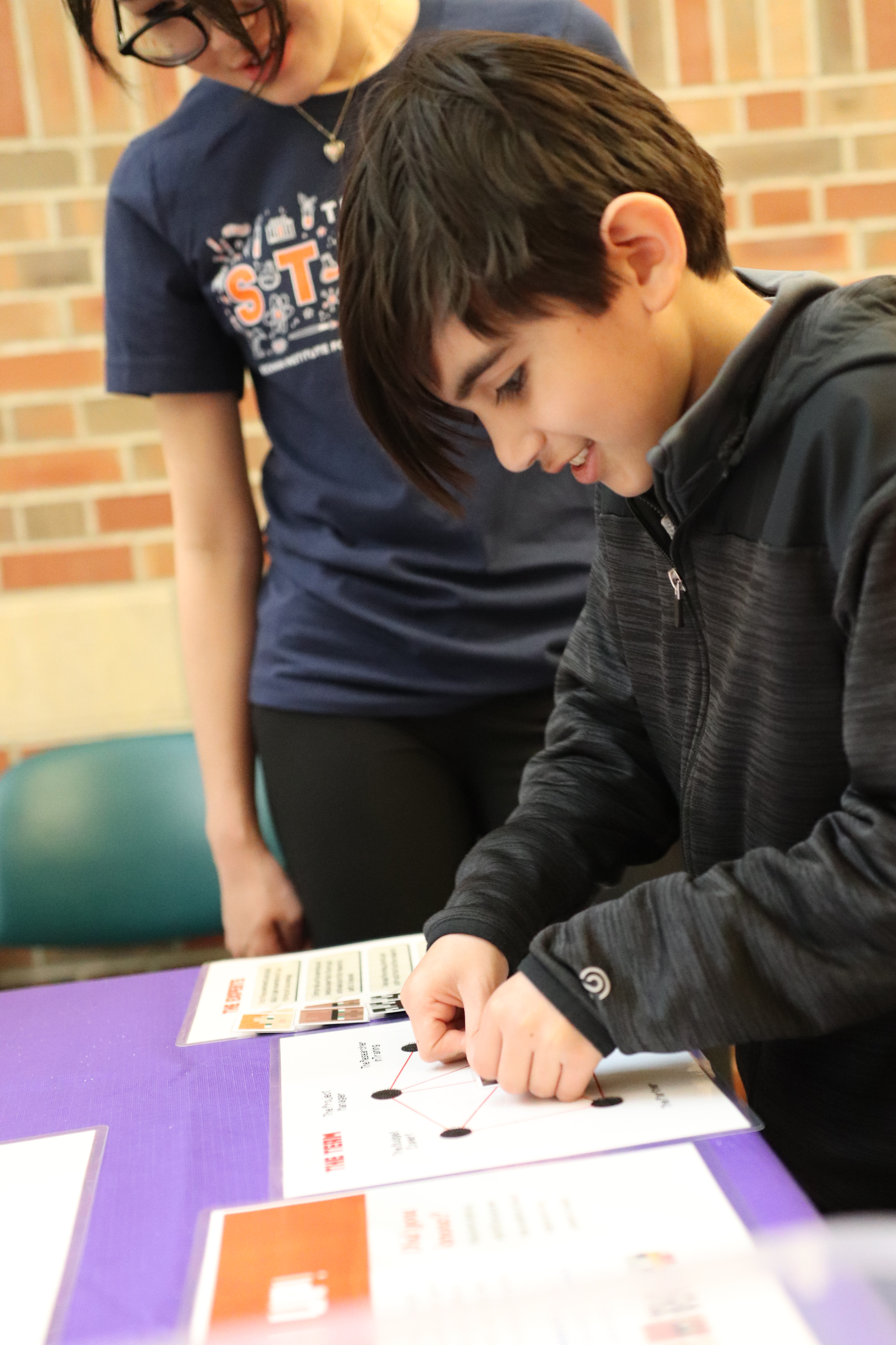 Child stands at table and places velcro pieces on a diagram.