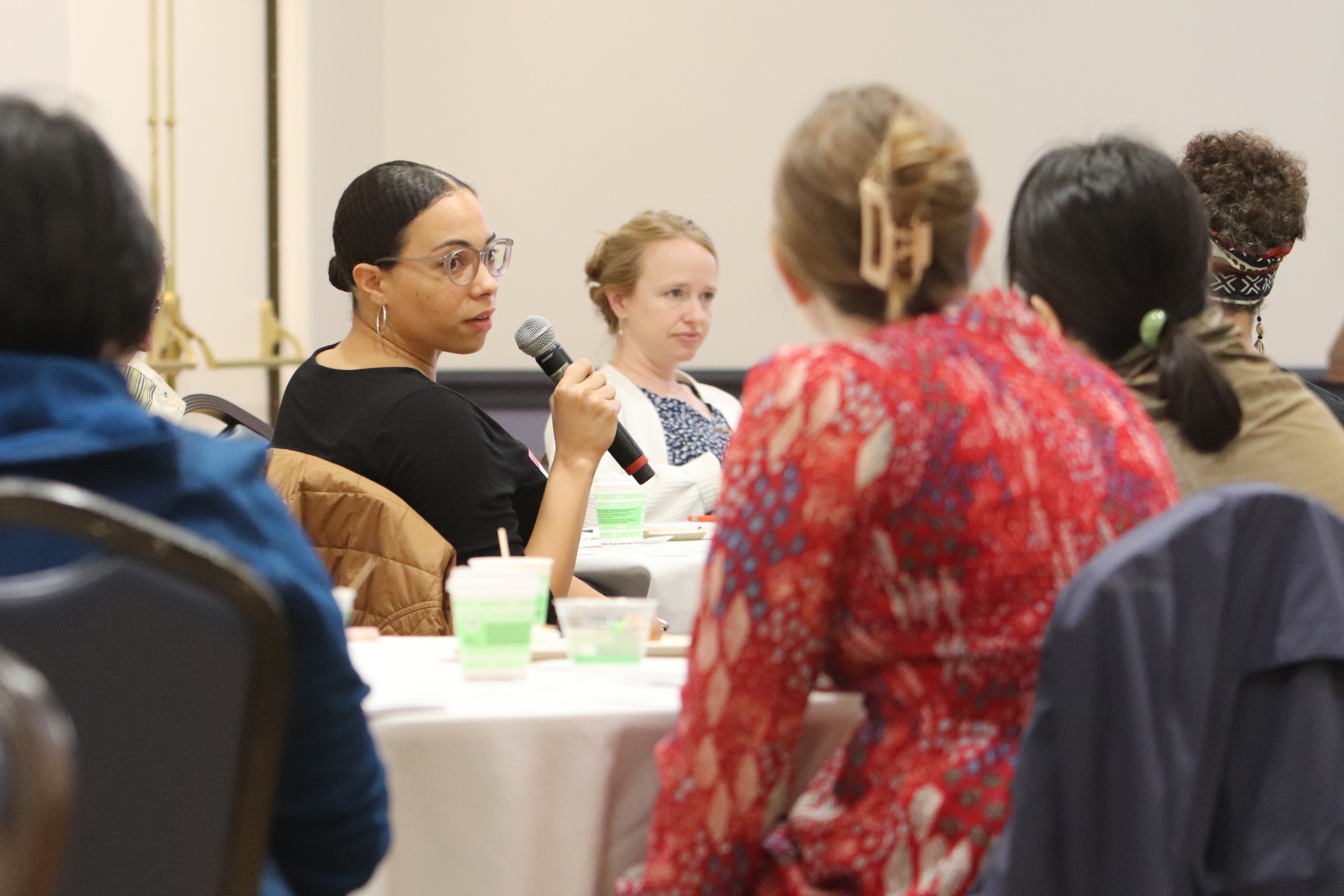Researchers gather around table at event as one speaks into a microphone