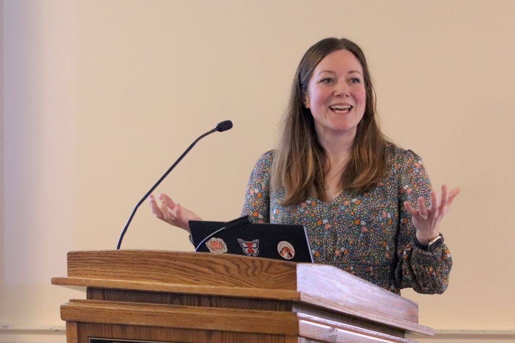 Rachel Garthe, presenting from a lectern, gestures and smiles at an unseen audience as she shares her vision.