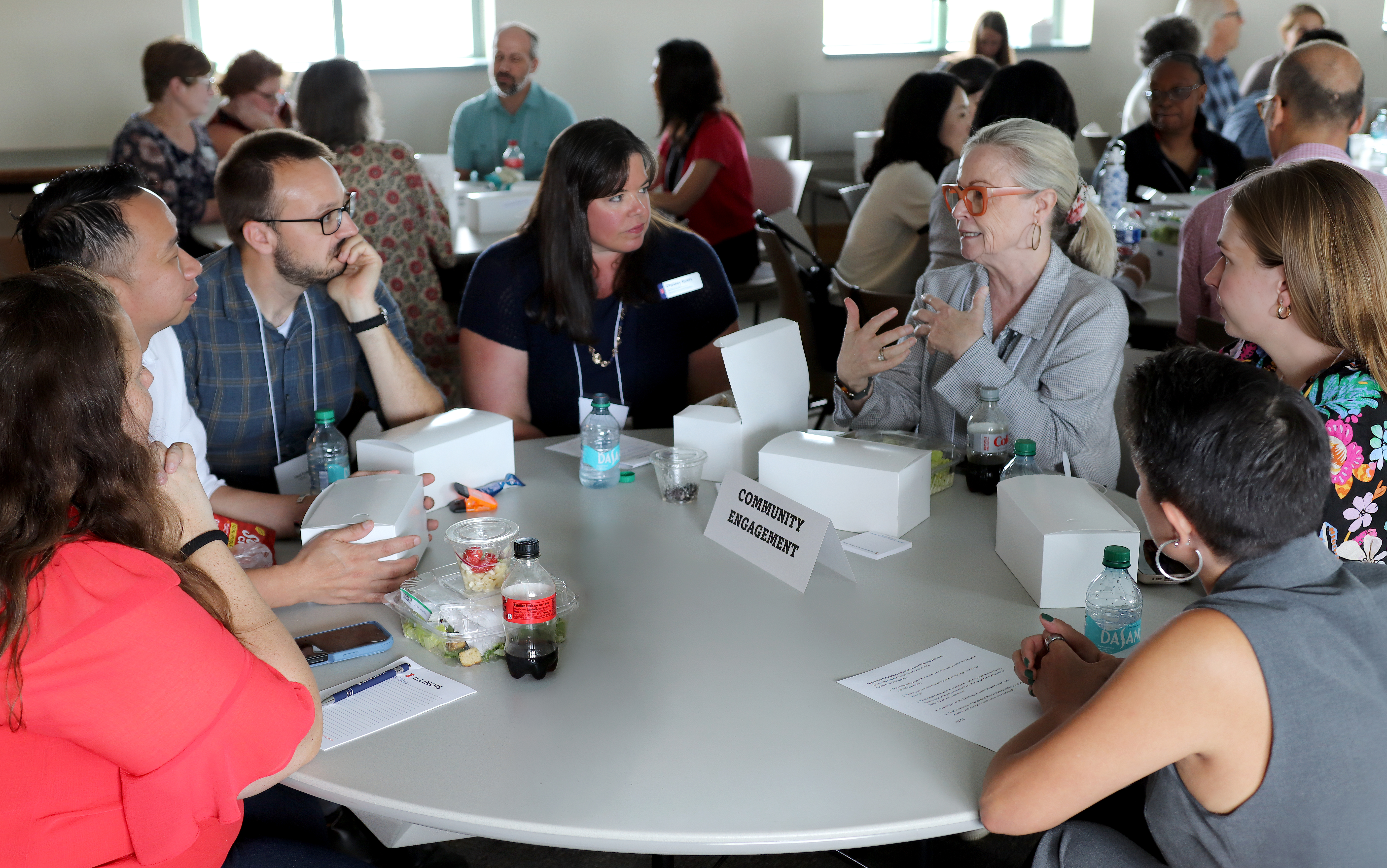 IHSI Affiliates gathered around a table. A table tent that reads "Community Engagement" sits in the center.