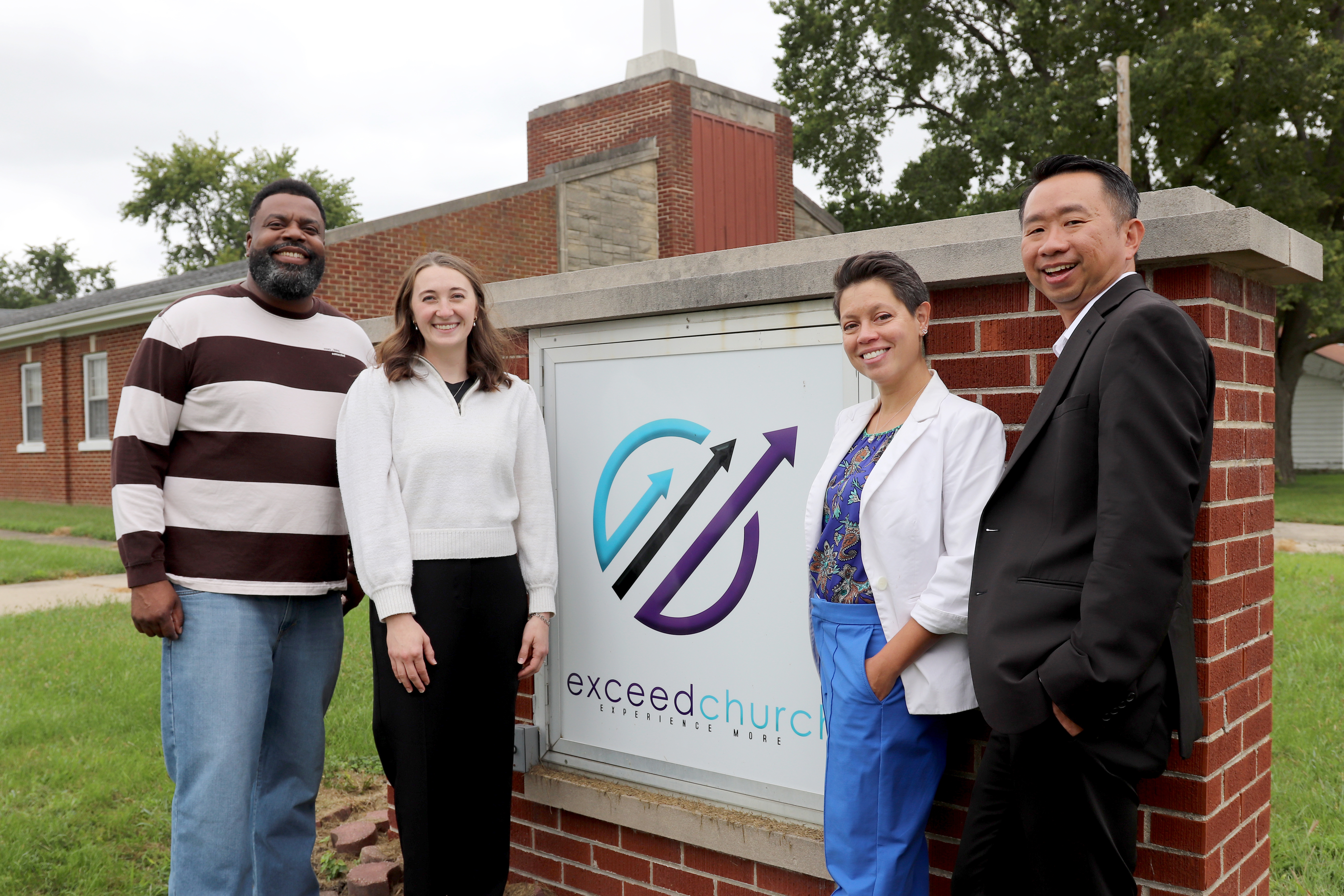 Pastor Jonathan Jackson, Kelsi Walters, Celina Trujillo, and Kevin Tan stand in front of the Exceed Church sign in Rantoul, Illinois