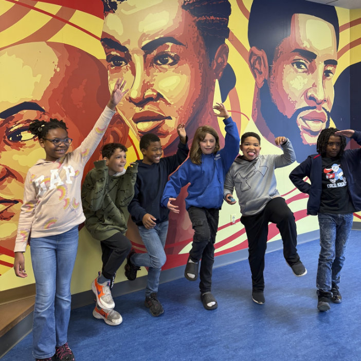 Exceed Church after-school program students in front of a mural at the School of Social Work