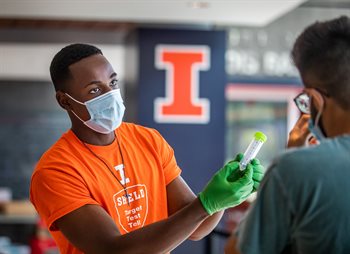 An Illinois student explaining to someone how to provide a saliva sample for the COVID test