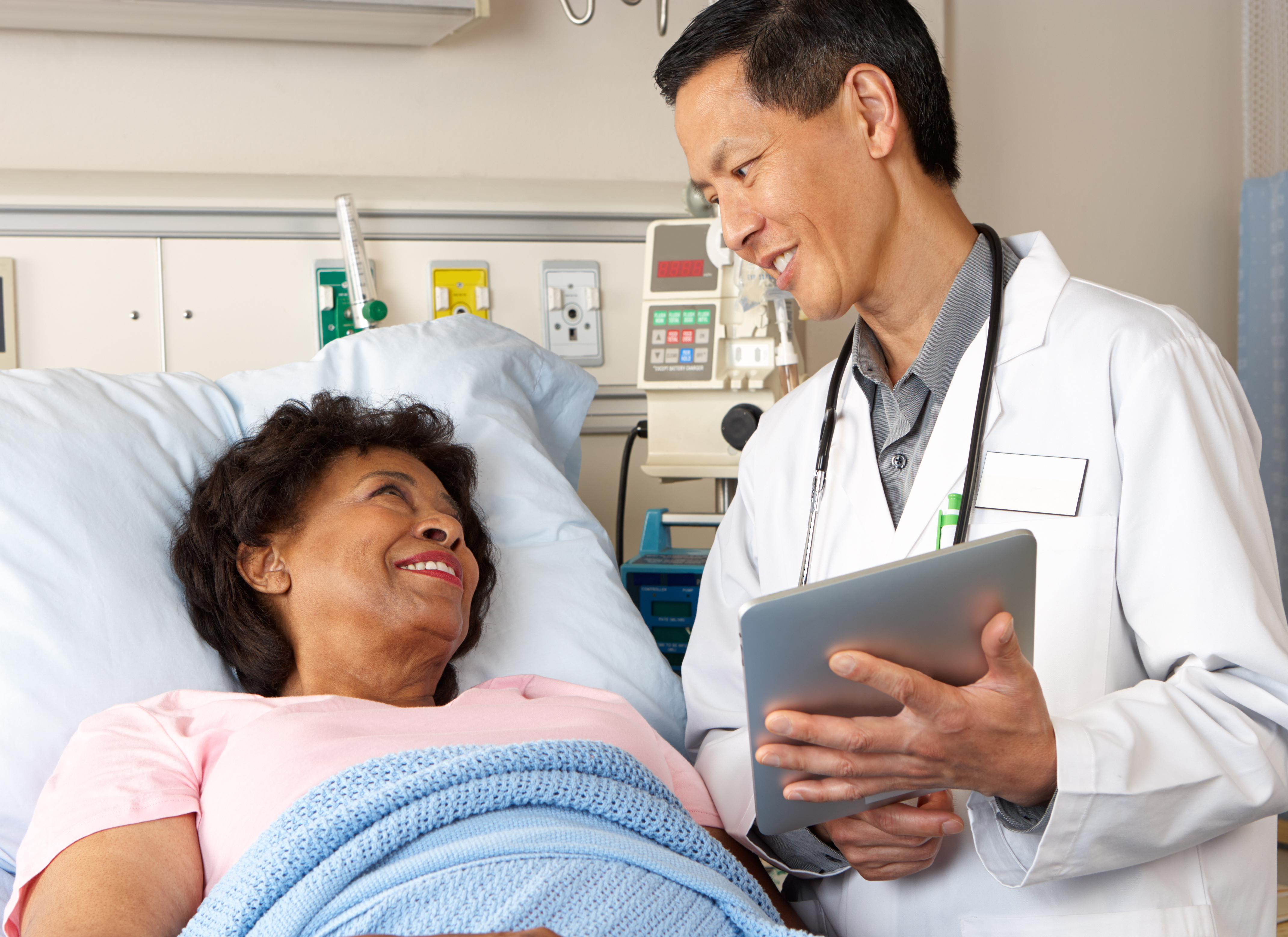 a doctor meets with a patient lying in a hospital bed