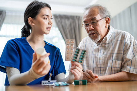 an at-home nurse discussing medication with elderly man