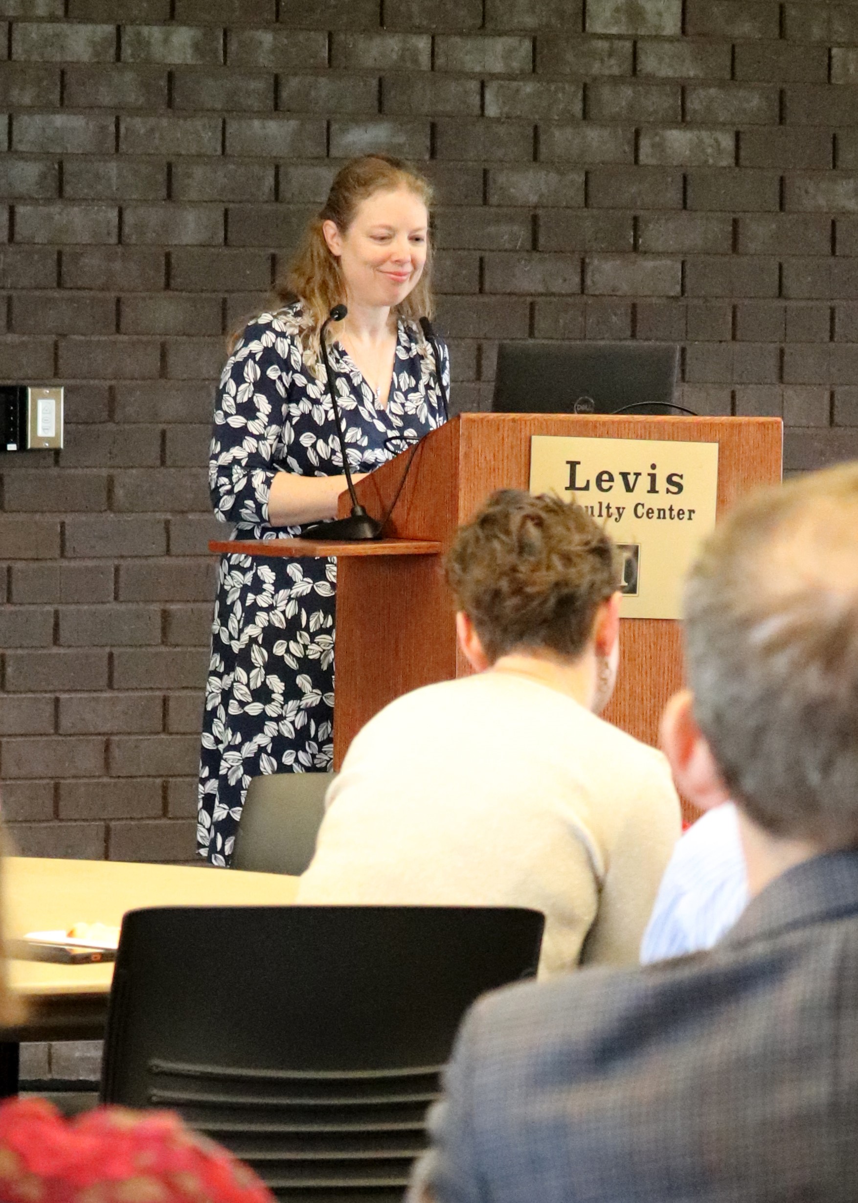 Annette McCoy stands at podium and looks down at notes while addressing an audience at the Emerging Research Leaders Academy celebration.